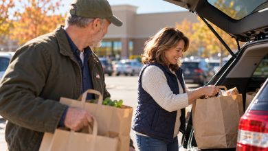 Veteran and spouse loading shopping bags into a car trunk in a sunny store parking lot